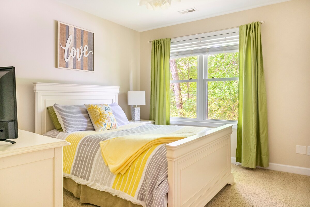 Guest bedroom with white furniture and bright yellow/gray bedding