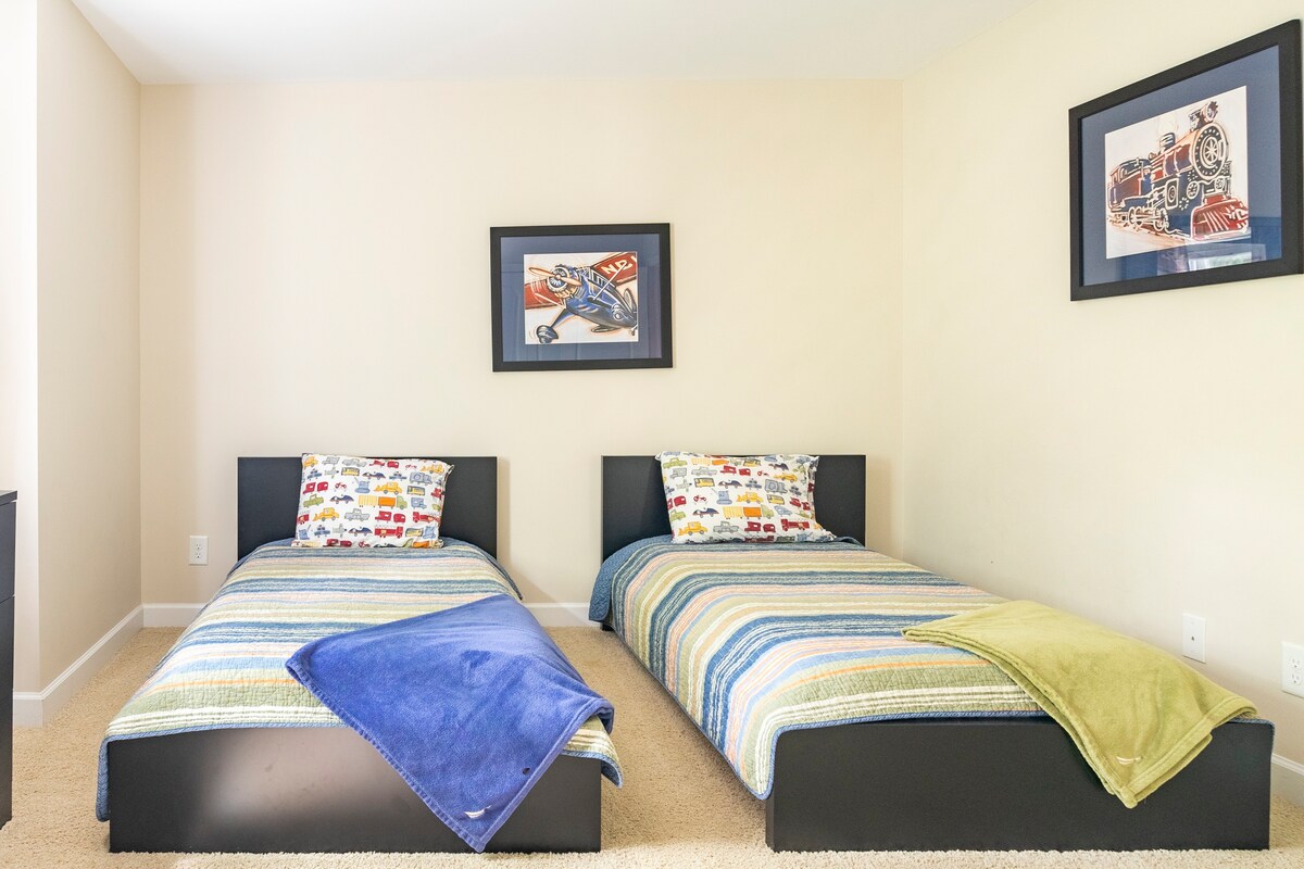 Kids bedroom with twin beds and train-themed artwork